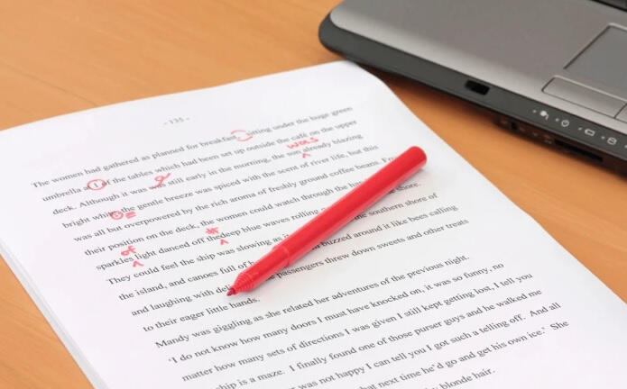 A picture of a block of text and a red marker with underlinings and notes in red, depicting proofreading marks.