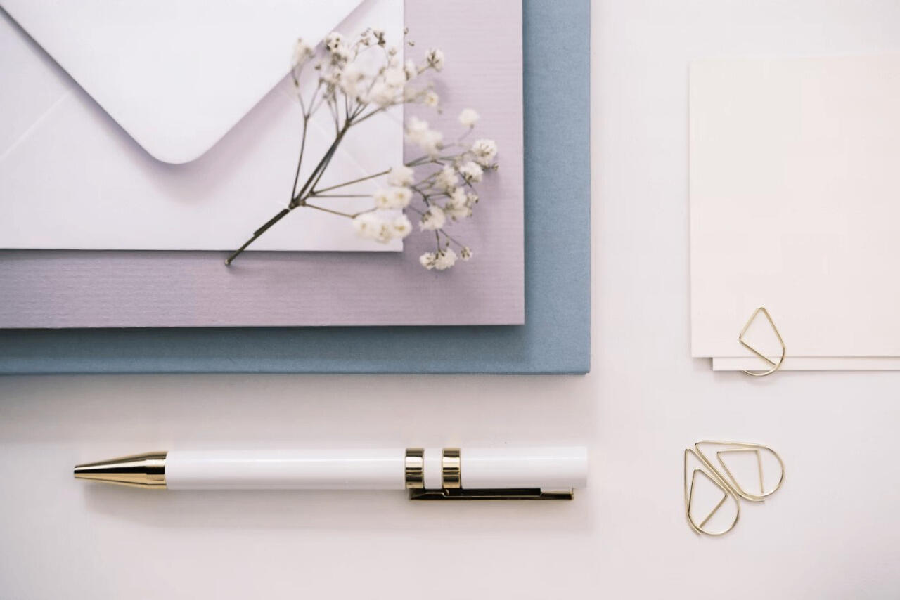 A notepad, a pen and a flower on a table.